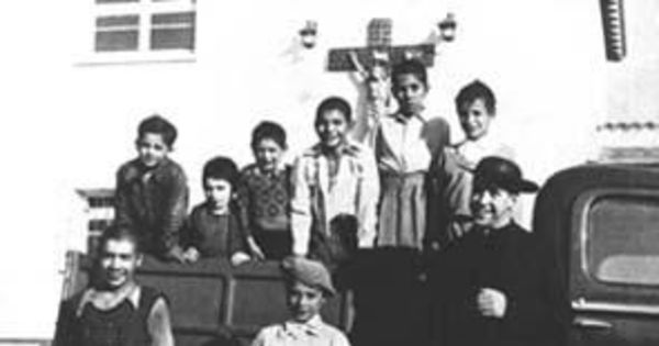 Padre Alberto Hurtado recogiendo niños de la calle en su camioneta verde, 1945