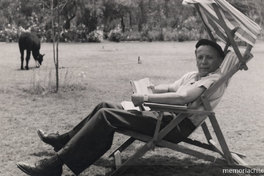 Humberto Díaz Casanueva sentado con un libro en las manos en el campo