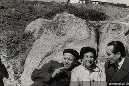 Humberto Díaz Casanueva apoyado en una roca junto a una mujer y un hombre