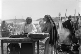 Dos mujeres feriantes en su puesto de la feria venden pan amasado