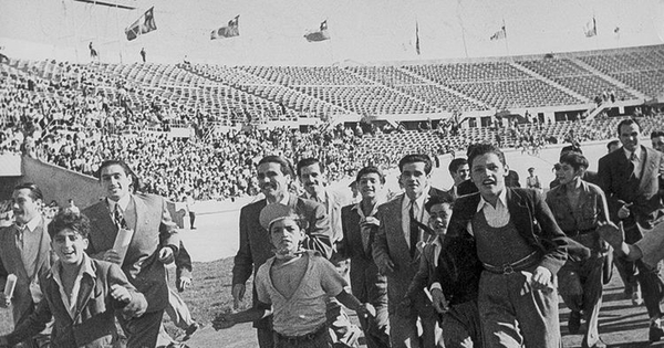 Pie de foto: Hinchas de fútbol corren por la pista de ceniza del Estadio Nacional, 1948