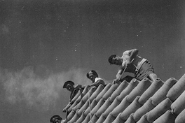 Trabajadores de la construcción junto a sacos de cemento, hacia 1960