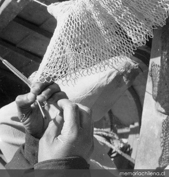 Pescador, detalle de su mano cosiendo una red, hacia 1960