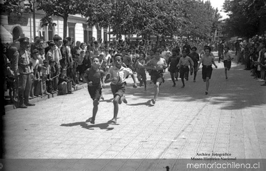 Niños corren durante competencia por celebración del Día del Roto Chileno en Plaza Yungay, 1944