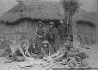 Grupo mapuche junto a un rewe, frente a su ruka