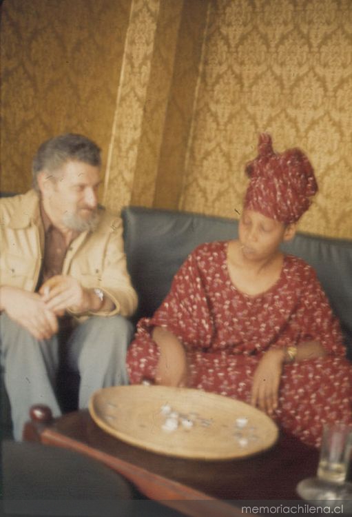Hans Ehrmann junto a mujer con traje africano rojo