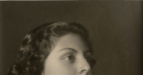 Joven mujer de vestido blanco con las manos sobre una figura [dragón de plaqué], entre 1930 y 1940