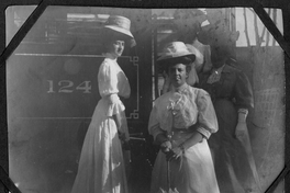 Cuatro señoras, con sombreros, posan en la escalera del tren, portan sombrillas