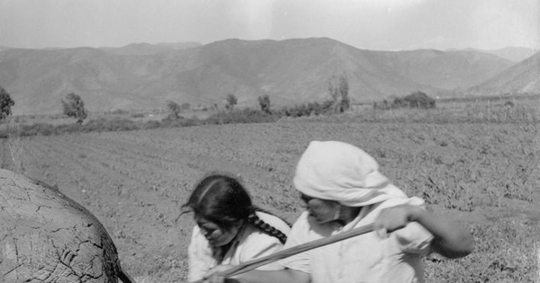 Mujeres campesinas sacando pan amasado de un horno de barro