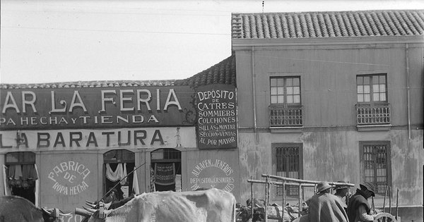 Tres hombres con sus animales de carga y carretas en la feria