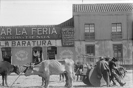 Tres hombres con sus animales de carga y carretas en la feria