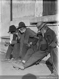 Tres hombres sentados, con ponchos y sombreros