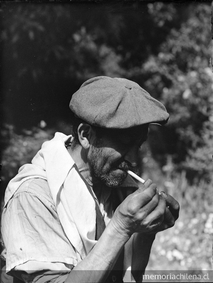 Hombre anciano de boina y camisa blanca prendiendo un cigarro