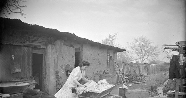 Mujer lavando un alto de ropa en la arteza en el patio de la casa