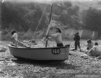Dos pescadores alistan el bote para salir a pescar rodeados de un grupo familiar sentado en la playa