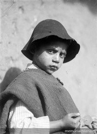 Niño con poncho y sombrero jugando con un runrún