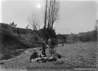 Niños ordenando la ropa lavada en el río; al fondo sus madres