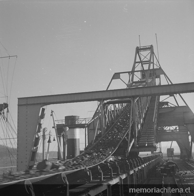 Pie de foto: Carbón conducido por la cinta transportadora hasta el cargador móvil, instalado en el extremo del muelle de embarque, 1940. Fotografía de Ignacio Hochhäusler.