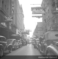 Pie de foto: Calle del centro de Santiago con carteles iluminados. Primera mitada del siglo XX. Fotografía de Ignacio Hochhäusler.