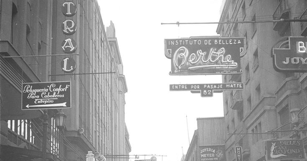 Pie de foto: Calle del centro de Santiago con carteles iluminados. Primera mitada del siglo XX. Fotografía de Ignacio Hochhäusler.