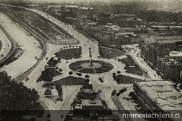 Pie de foto: Plaza Baquedano desde el aire en 1934En Memorándum sobre "Proyecto Transformación definitiva Comuna de Providencia": obsequio de su Junta de Vecinos. Santiago: Impr. Universo, 1934. p. 3, con el pie de foto "Entrada a la Comuna de Providencia. Plaza Baquedano".