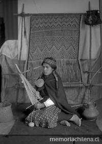 Pie de foto: Mujer araucana sentada junto a telar, enrollando lana. 1920