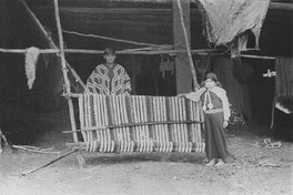 Niña y joven mapuche junto a un telar