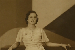 Mujer posando de pie, con un vestido entallado, amarrado en la cintura, entre 1940 y 1950