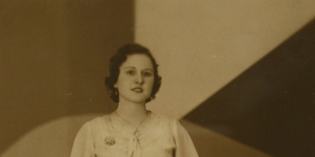 Mujer posando de pie, con un vestido entallado, amarrado en la cintura, entre 1940 y 1950