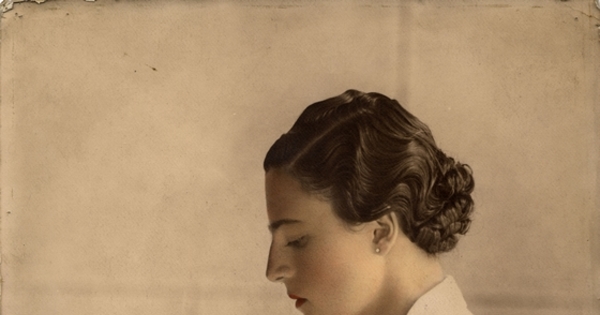 Mujer posando sentada y de perfil, de pelo corto ondulado y vestido blanco con cinturón, entre 1930 y 1940