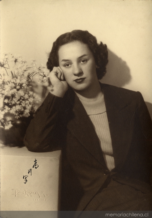 Mujer joven sentada y apoyada sobre un mueble con un jarro de flores, entre 1930 y 1940