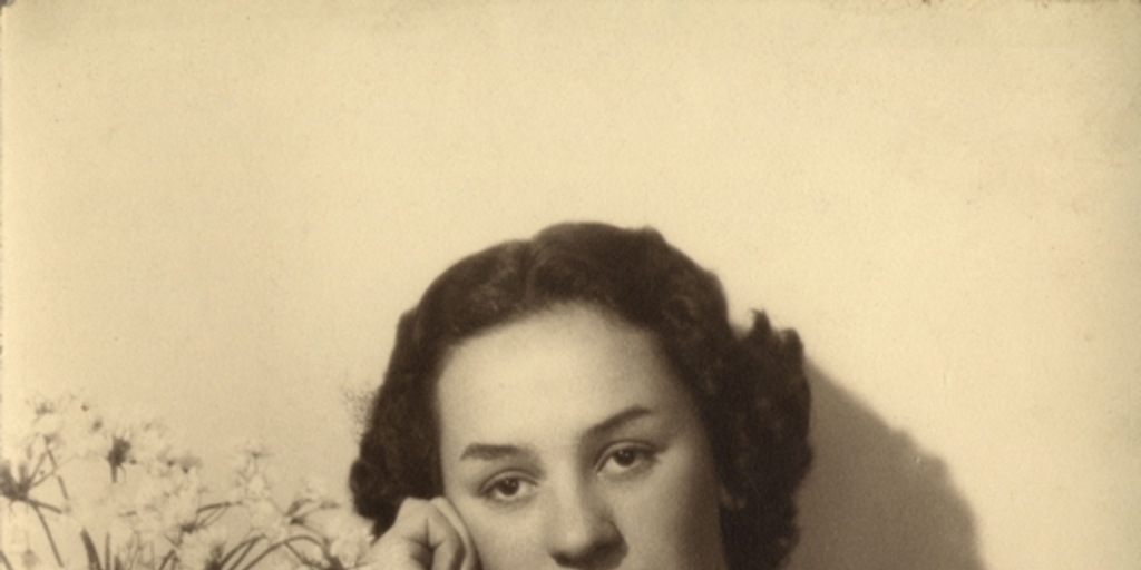 Mujer joven sentada y apoyada sobre un mueble con un jarro de flores, entre 1930 y 1940