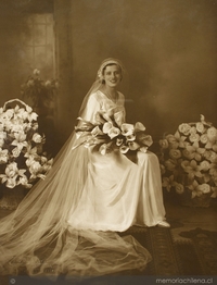 Mujer vestida de novia con dos ramos grandes de flores a su alrededor y un ramo pequeño en sus manos, entre 1928 y 1930